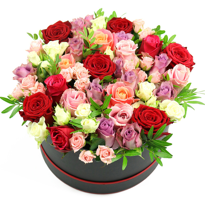 In this photograph, a dramatic floral hatbox sits alone against a crisp white background, the minimalist setting drawing every ounce of attention to the intricate rose display. The container is an elegant black cylinder, reminiscent of a classic hatbox, with a slim ribbon of red trim circling the lower edge, adding a refined touch of colour that hints at a luxurious gift you might send to a loved one in Chessington. Overflowing from this base is a meticulously arranged dome of roses, so abundant that they spill outward and upward in a soft, rounded mound of petals. The colour story is rich and layered: velvety crimson roses suggest classic romance, while shades of scarlet and deep ruby weave intensity through the design. Beside them, soft blush pink and vivid fuchsia blooms introduce a playful, tender note, echoing the joyful energy of celebrations nearby in places like Hook Road or around Chessington North. Warm coral and delicate peach roses offer a gentle, sun-kissed glow, blending seamlessly with creamy white and ivory flowers that provide clarity and brightness. Adding sophistication, roses in lavender and muted purple punctuate the arrangement, their cool tones balancing the warmer hues and giving the piece a contemporary edge. Each flower appears at a different stage of bloom, from tightly curled buds with a smooth, satin surface to fully open rosettes where every petal is visible in layered spirals. Tucked between the blossoms are fine sprigs of greenery, perhaps ruscus or eucalyptus, whose fresh green tones and slender leaves lend texture and a hint of woodland fragrance. The composition feels both indulgent and considered, ideal for same-day delivery for anniversaries, Valentine's surprises, or heartfelt congratulations across Chessington, where a show-stopping bouquet like this can transform an ordinary table into the centrepiece of the occasion.